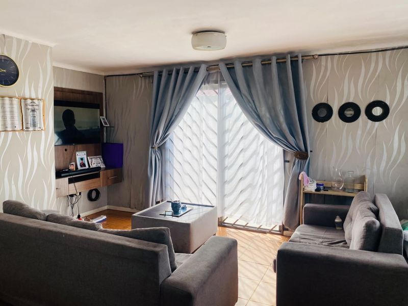 A comfortable living room featuring tiled flooring, a built-in media console, and a sliding glass door providing natural light.
