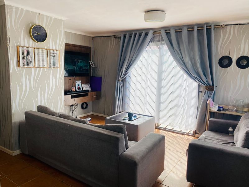 A comfortable living room featuring tiled flooring, a built-in media unit, and a sliding glass door providing access to the outdoors.