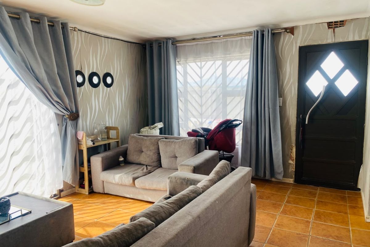 A living room featuring tiled flooring and a secure front entrance, currently requiring cosmetic updates to the wall finishes.