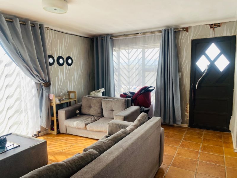 A living room featuring tiled flooring and a secure front entrance, currently requiring cosmetic updates to the wall finishes.