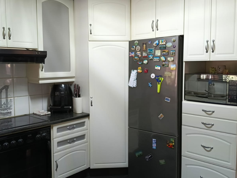 A functional kitchen featuring white cabinetry, granite countertops, a built-in oven with hob, extractor fan, and a dedicated space for a microwave.