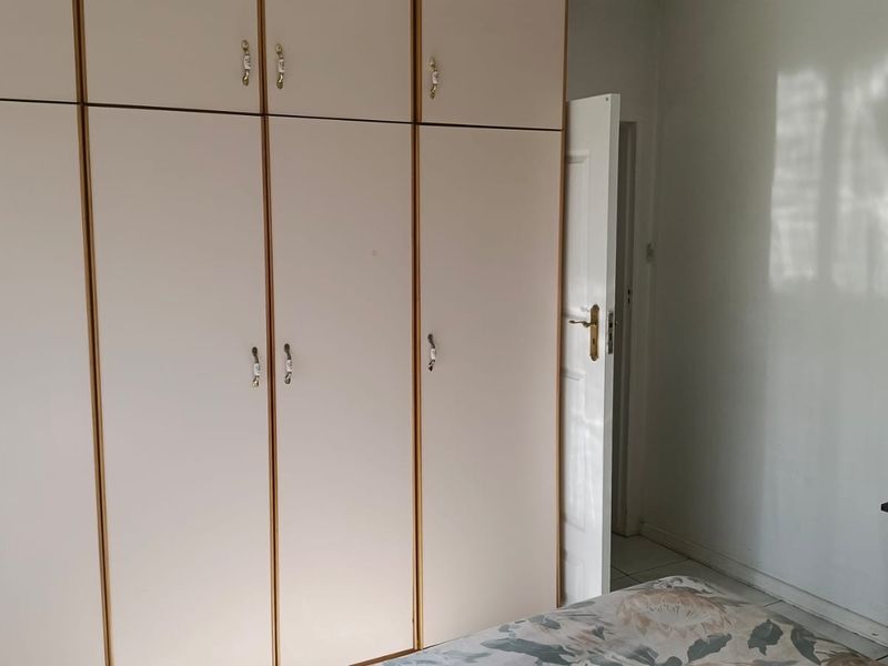 A bedroom featuring floor-to-ceiling built-in cupboards with light-toned doors and a standard internal door.