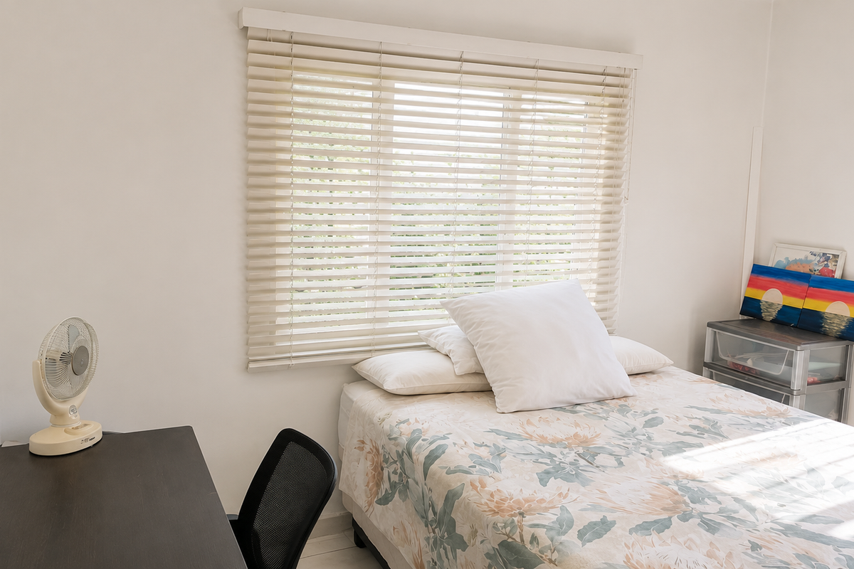 A bright bedroom featuring neutral walls and fitted venetian blinds, providing a clean and functional space.