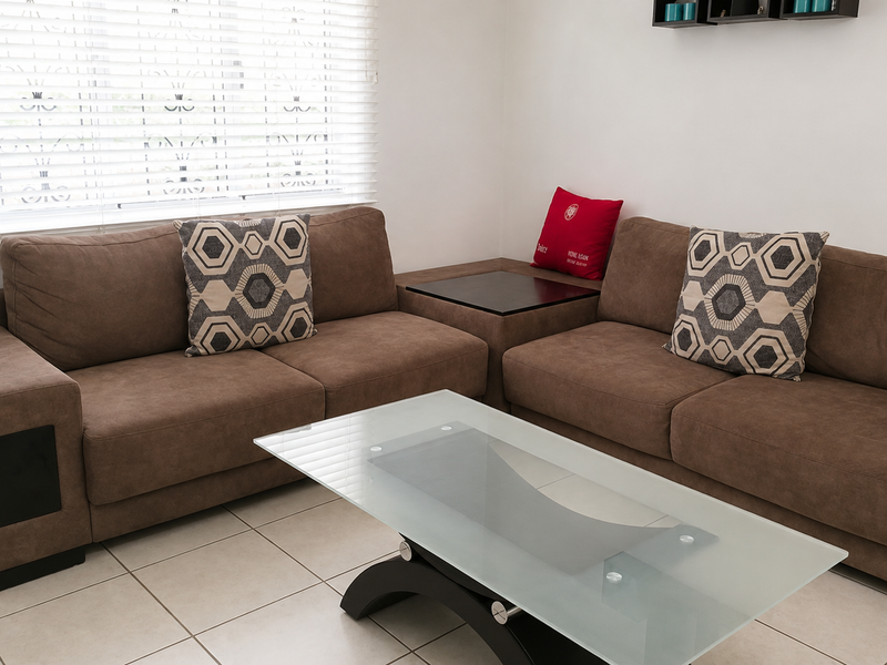 A living room area featuring neutral ceramic floor tiles and white venetian blinds, providing a clean and functional space.
