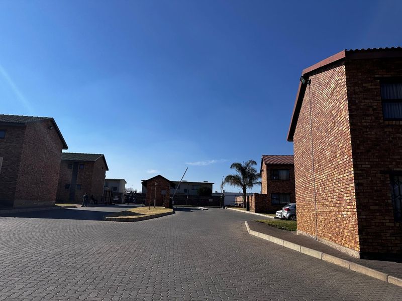 Exterior view of an apartment complex featuring face brick buildings, paved driveways, and a secure gated entrance.