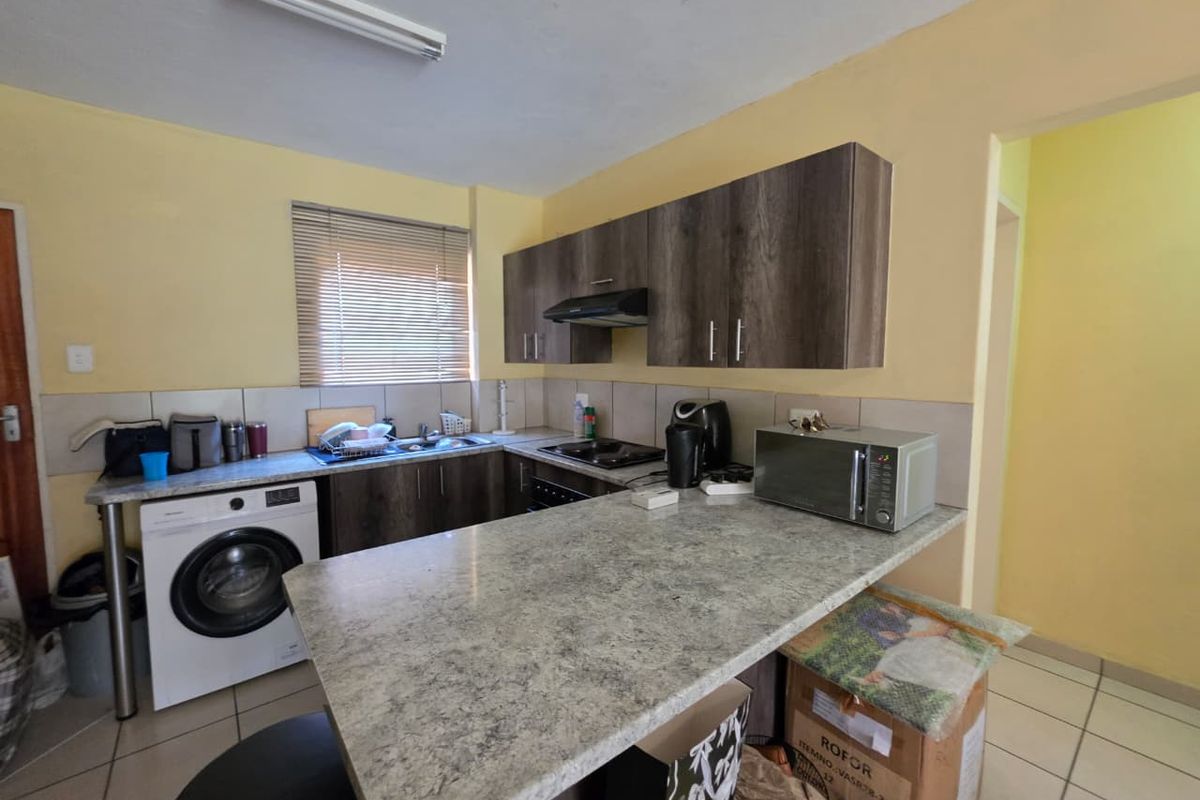 Functional kitchen featuring laminate cabinetry, stone-look countertops, built-in hob with extractor, and integrated laundry space, offering a practical layout for daily use.