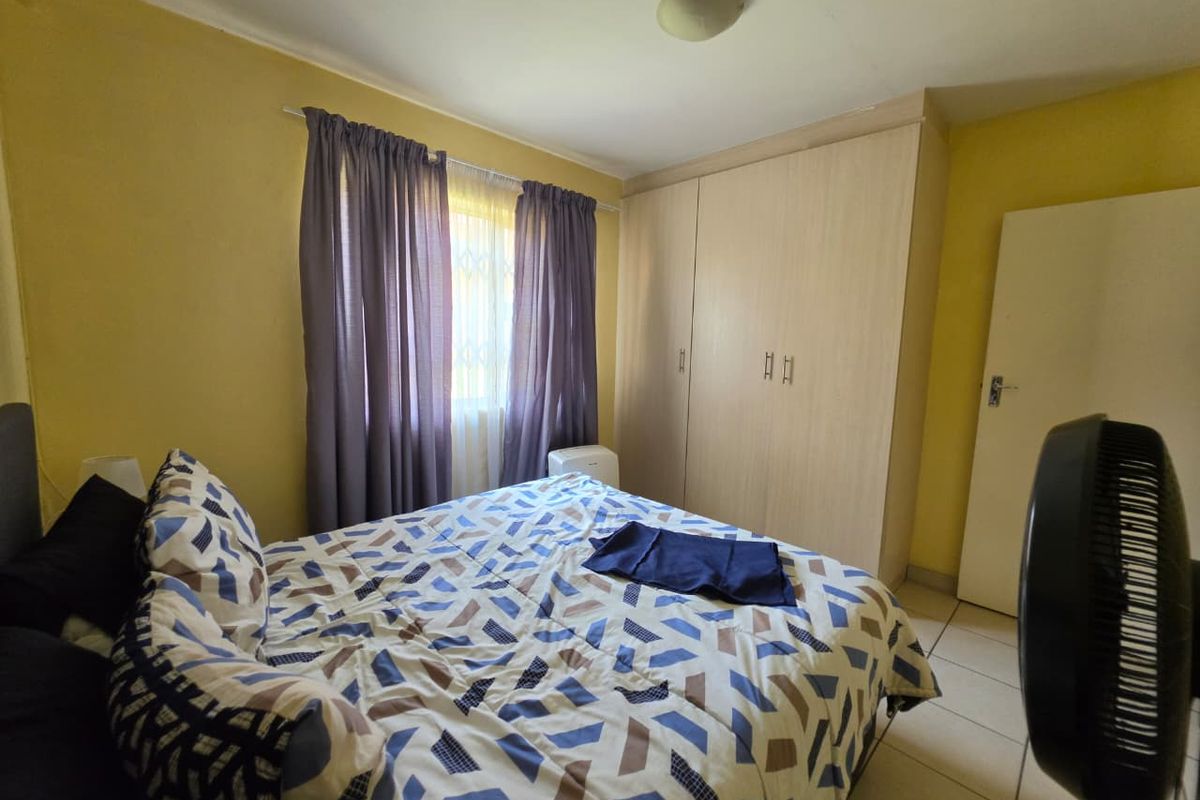A functional bedroom featuring tiled flooring, a built-in wardrobe, and a window with security gate protection.