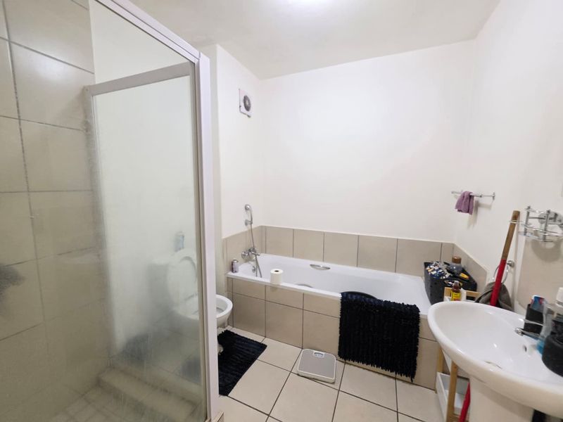 A functional bathroom featuring a separate shower enclosure, bathtub, pedestal basin, and toilet with neutral tiled finishes.