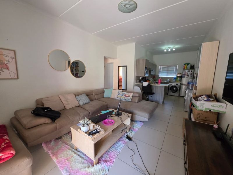 Open-plan living area featuring tiled flooring and a functional kitchen with built-in cabinetry and an island, creating a combined living and dining space.