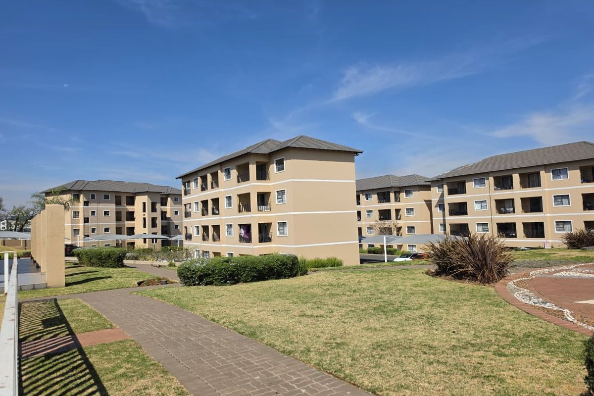 A view of the apartment complex grounds featuring well-maintained lawns, paved walkways, and multi-story residential buildings with balconies.