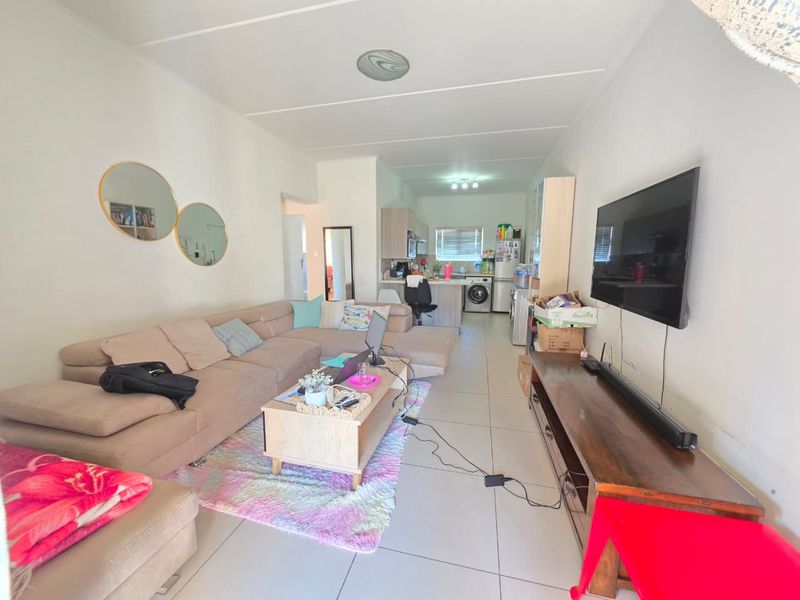 Open-plan living area featuring tiled flooring and a functional kitchen space with cabinetry and an island, creating a versatile living environment.