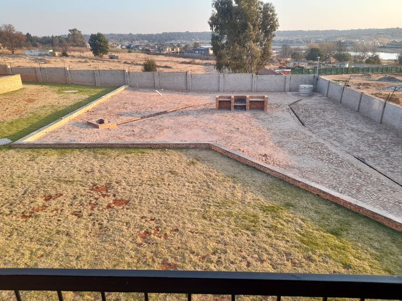 Spacious rear yard featuring a paved area, built-in brick braai, and perimeter walling, offering potential for landscaping and outdoor entertainment development.