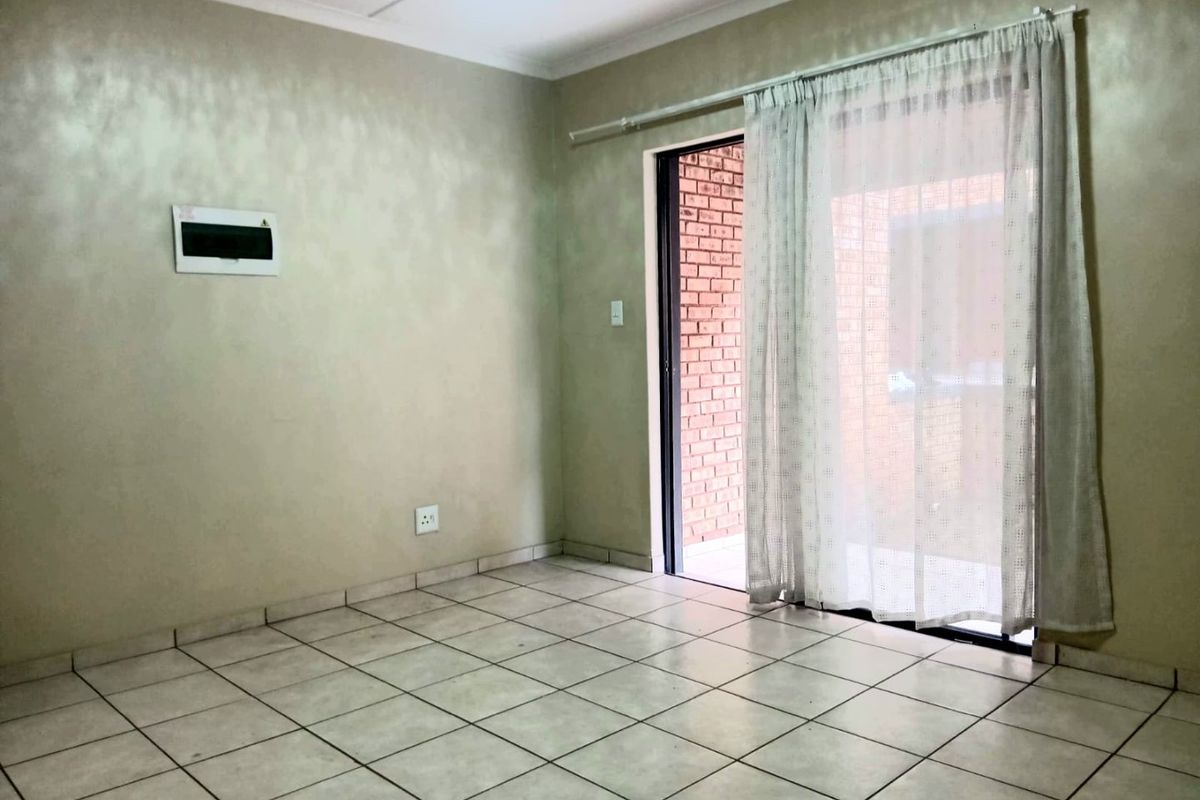 An empty living room featuring tiled flooring and a sliding glass door providing access to an outdoor area.