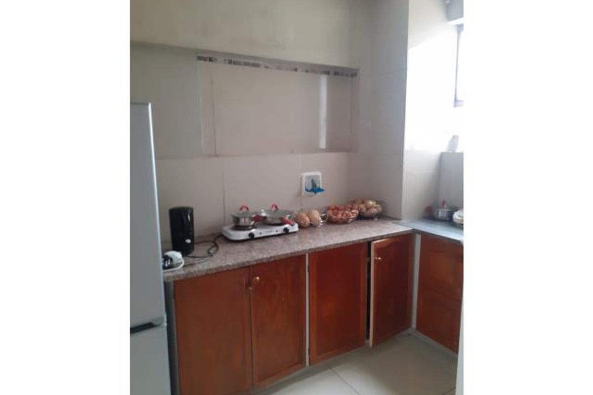 A functional kitchen featuring wooden cabinetry, granite countertops, and tiled backsplash, providing a practical workspace for daily meal preparation.