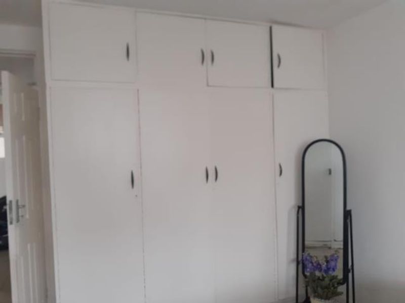 A bedroom featuring floor-to-ceiling built-in cupboards with overhead storage compartments, providing ample storage space.