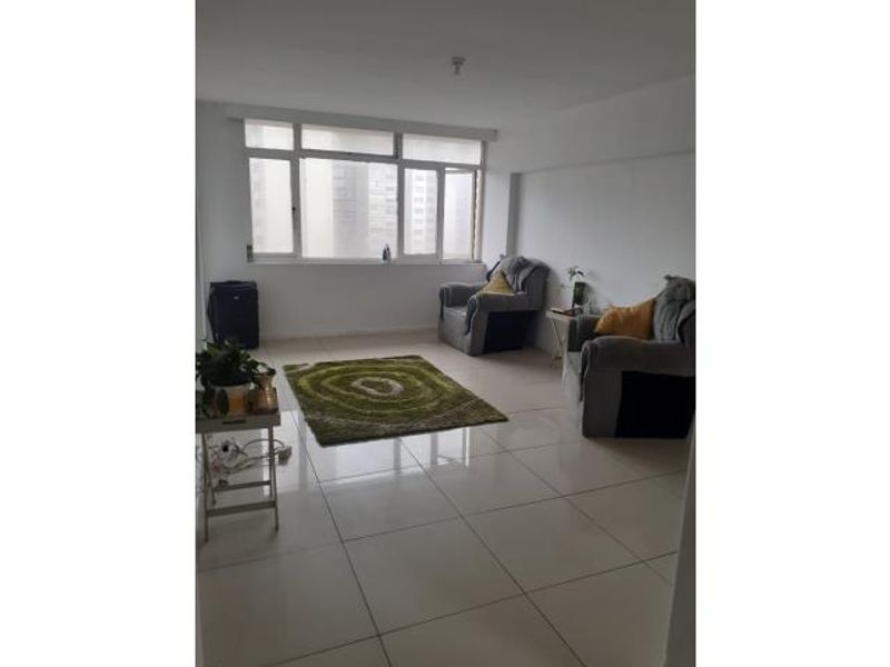 A bright living room featuring large windows and neutral tiled flooring, offering a clean and functional space ready for personalization.