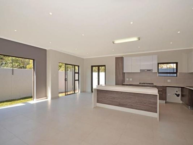 Spacious open-plan kitchen and living area featuring modern cabinetry, a central island, tiled floors, and large sliding doors leading to the exterior.