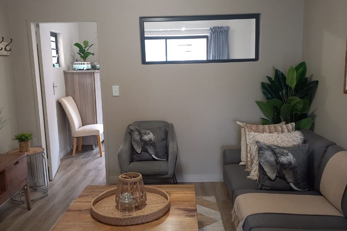 A well-maintained living room featuring neutral wall tones, laminate flooring, and decorative cove cornicing, providing a comfortable and inviting atmosphere.