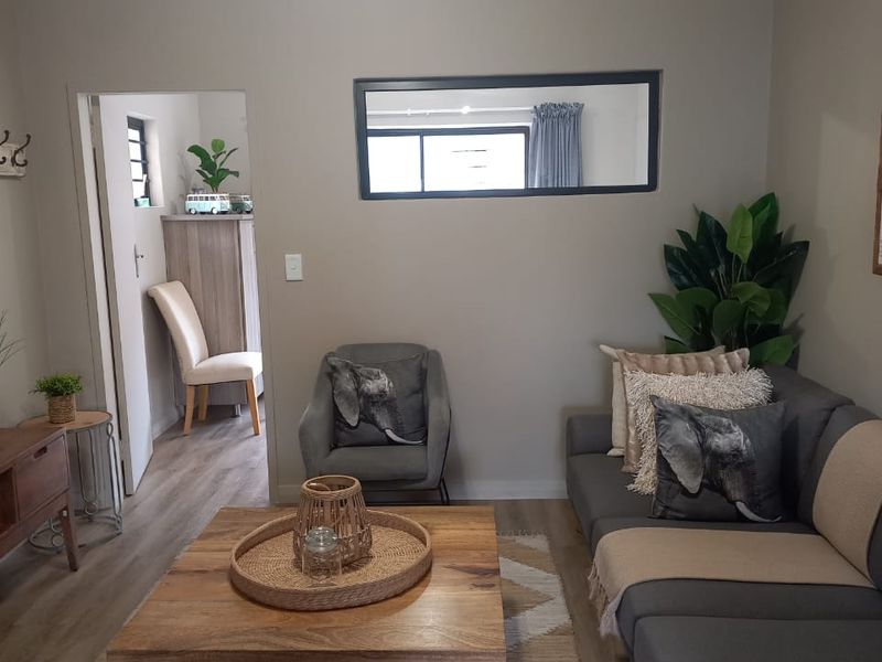 A well-maintained living room featuring neutral wall tones, laminate flooring, and decorative cove cornicing, providing a comfortable and inviting atmosphere.