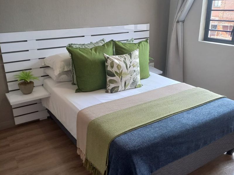 A well-maintained bedroom featuring durable laminate flooring and a window fitted with security burglar bars.