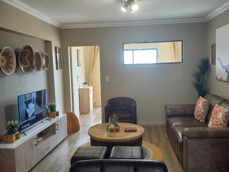 A well-maintained living room featuring laminate flooring, cove cornicing, and a recessed wall niche, providing a comfortable and functional living space.