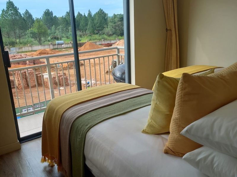 A bedroom featuring laminate flooring and a large sliding glass door that opens onto a balcony with an exterior view.