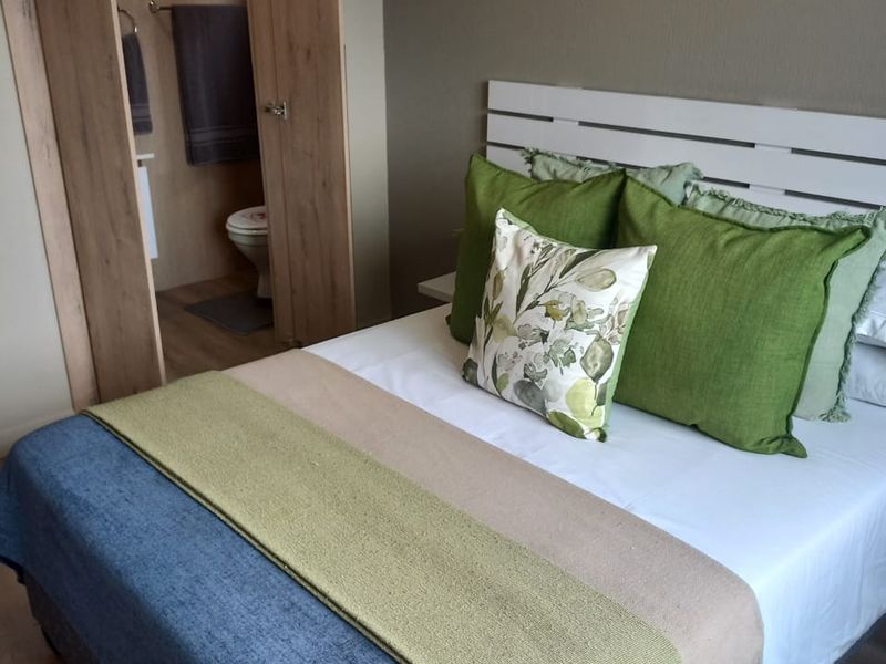 A well-maintained bedroom featuring laminate flooring and direct access to an en-suite bathroom with neutral wall finishes.