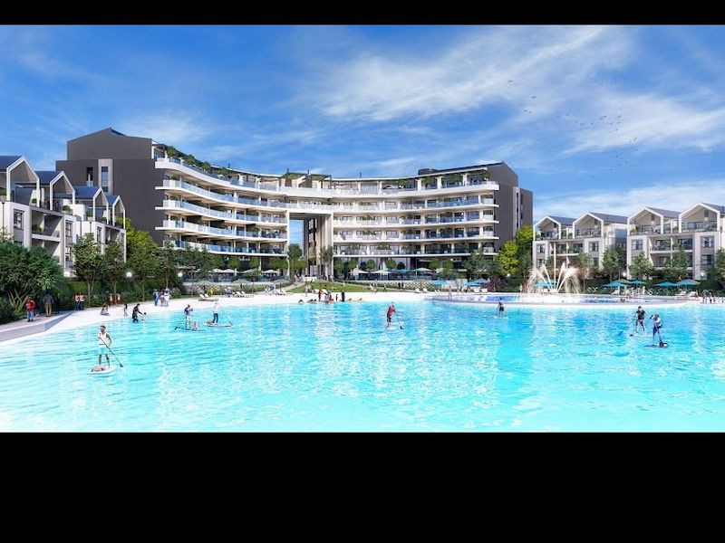 A large communal swimming pool and fountain area set within a modern apartment complex with landscaped surroundings.