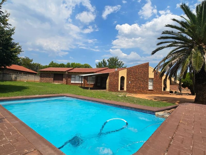 A spacious backyard featuring a swimming pool with brick paving and a view of the facebrick house exterior.