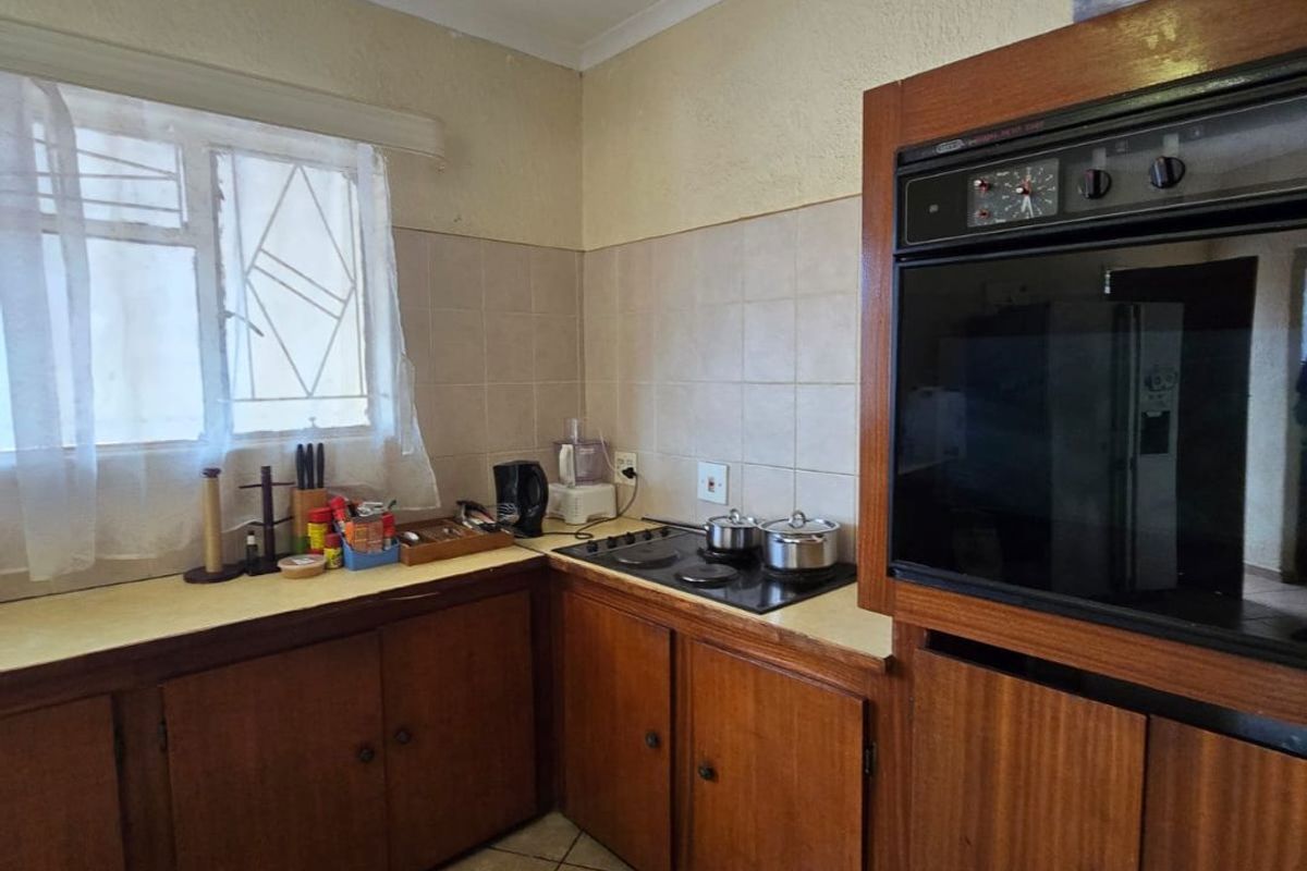 A functional kitchen featuring built-in wooden cabinetry, a built-in oven, electric hob, and ceramic tile finishes, offering potential for modernization.