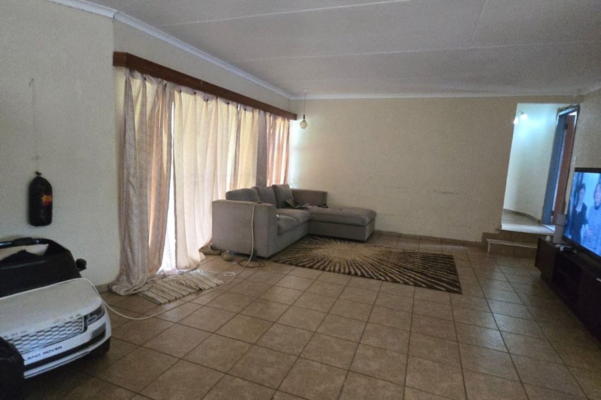 Spacious living room featuring tiled flooring and coved ceilings, offering a blank canvas for potential interior updates and modernization.