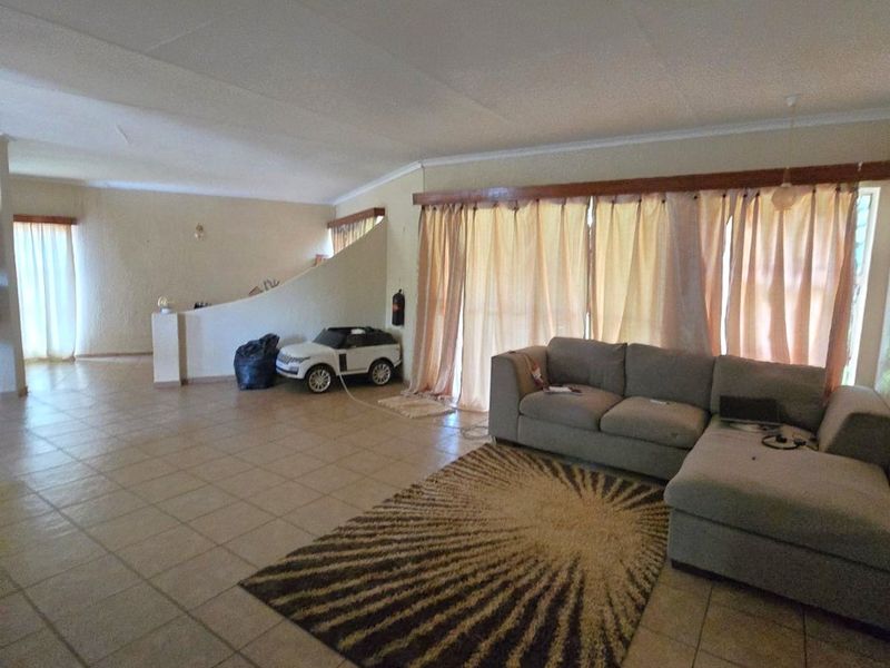 Spacious open-plan living area featuring large sliding glass doors, tiled flooring, and a central partition wall, offering a versatile layout for modern living.