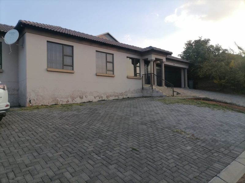 Front elevation of a single-story house featuring a paved driveway, garage, and entrance porch, showing visible signs of exterior wall damp and paint deterioration.
