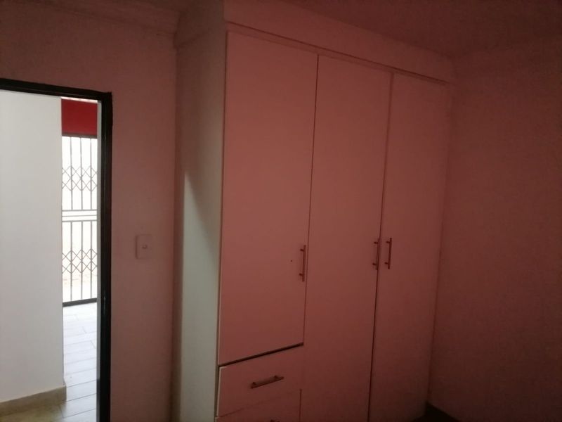 A bedroom featuring a built-in wardrobe and a doorway leading to an exterior area with a security gate.