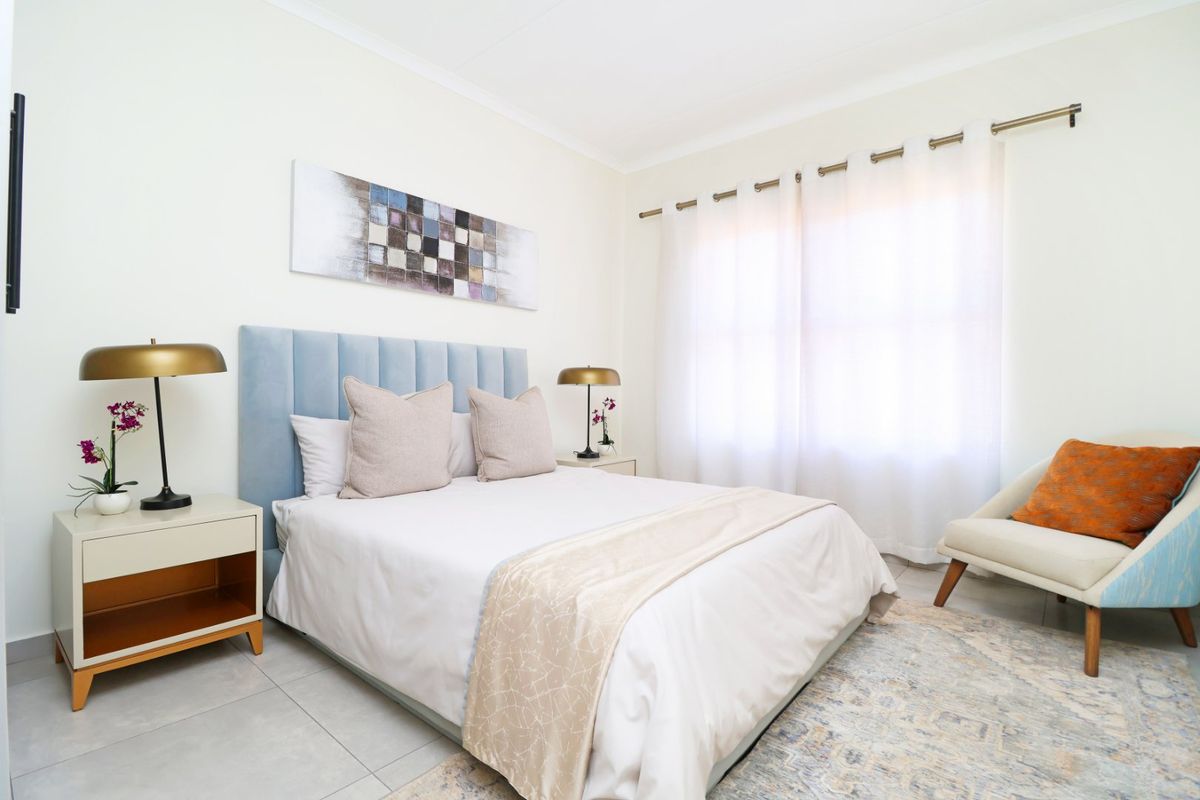 A well-maintained bedroom featuring neutral tiled flooring, soft wall tones, and a curtain rod, creating a bright and comfortable living space.