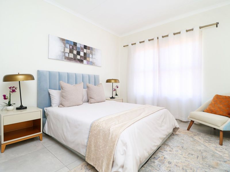 A well-maintained bedroom featuring neutral tiled flooring, soft wall tones, and a curtain rod, creating a bright and comfortable living space.