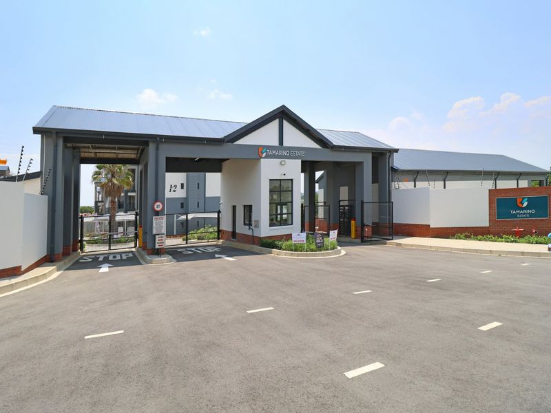 The main entrance and security gatehouse of Tamarino Estate, featuring modern architecture, paved access, and secure perimeter fencing.