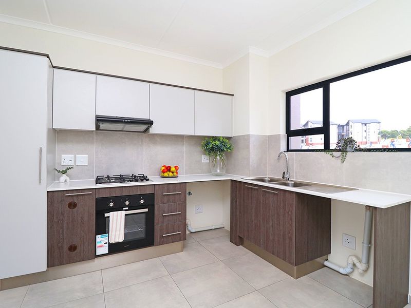 Modern kitchen featuring two-tone cabinetry, gas hob, built-in oven, extractor fan, and tiled backsplash with ample counter space.