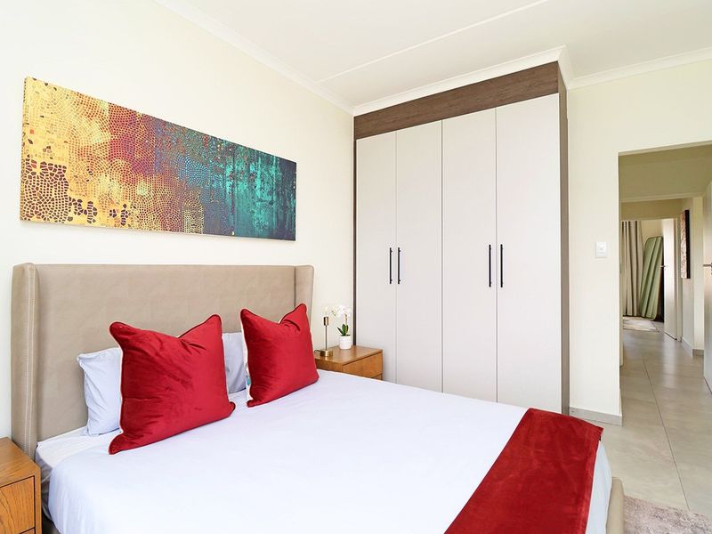 A well-maintained bedroom featuring neutral tiled flooring, a modern built-in wardrobe with clean lines, and coved ceiling detailing.