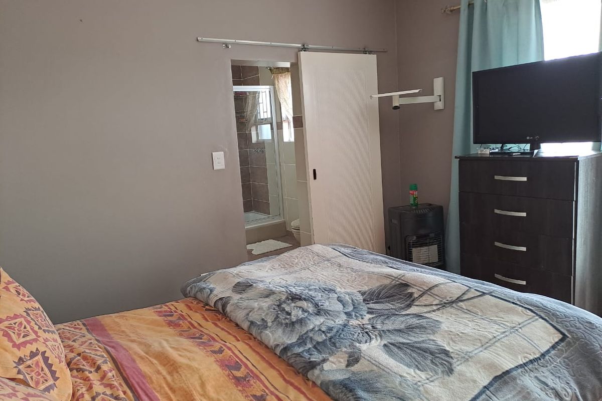 A bedroom featuring a sliding door leading to an en-suite bathroom with tiled finishes.