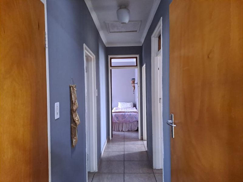 A functional hallway featuring tiled flooring and wooden doors, providing access to multiple rooms within the home.