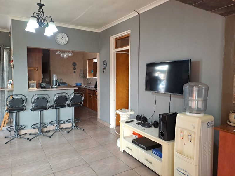Open plan living area featuring tiled flooring and a breakfast bar connecting to the kitchen space.