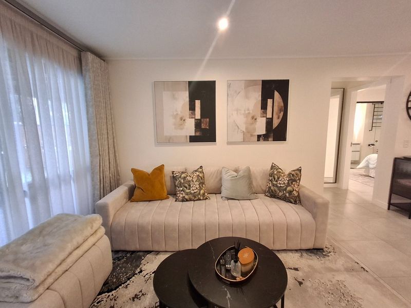 A well-maintained living room featuring neutral tiled flooring, recessed lighting, and a large sliding glass door providing natural light.