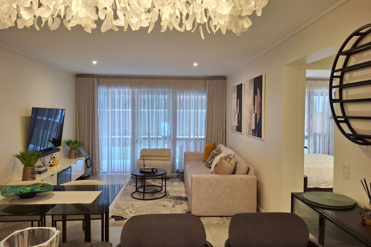 A well-maintained living room featuring tiled flooring, recessed lighting, and large sliding glass doors that provide access to the balcony area.