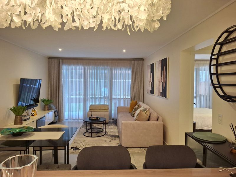 A well-maintained living room featuring tiled flooring, recessed lighting, and large sliding glass doors that provide access to the balcony area.