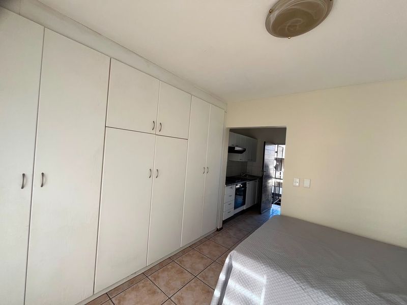 Bedroom featuring extensive built-in cupboards, tiled flooring, and direct access to the adjacent kitchen area.