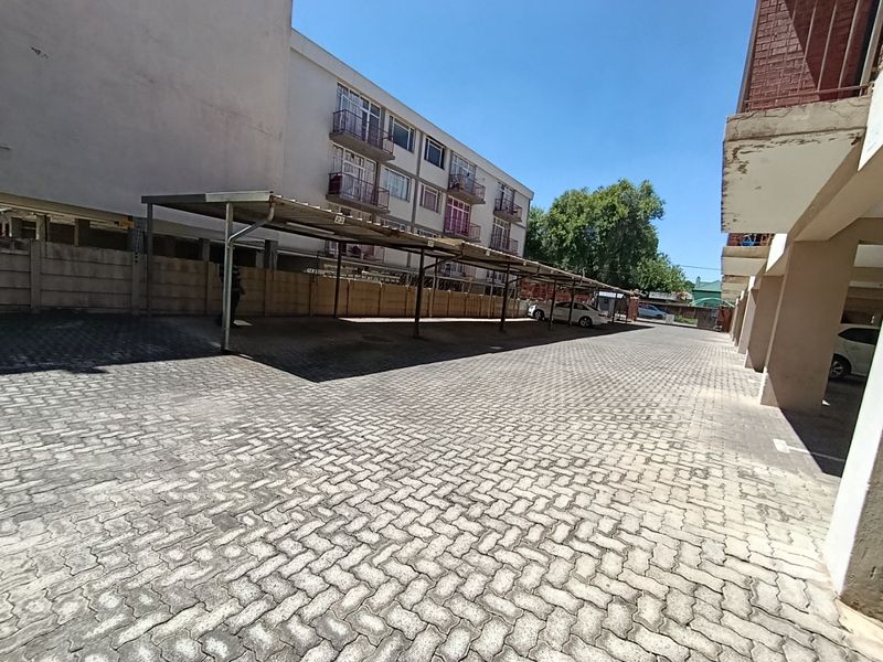 Exterior view of the apartment complex parking area featuring paved driveway and covered carport structures.