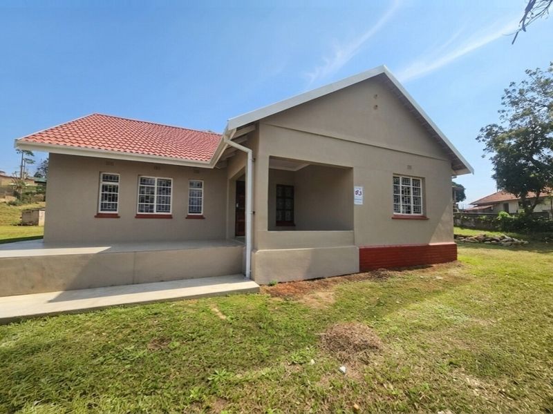 A well-maintained single-story house featuring a tiled roof, covered porch, and security bars on the windows, set on a spacious lawn.