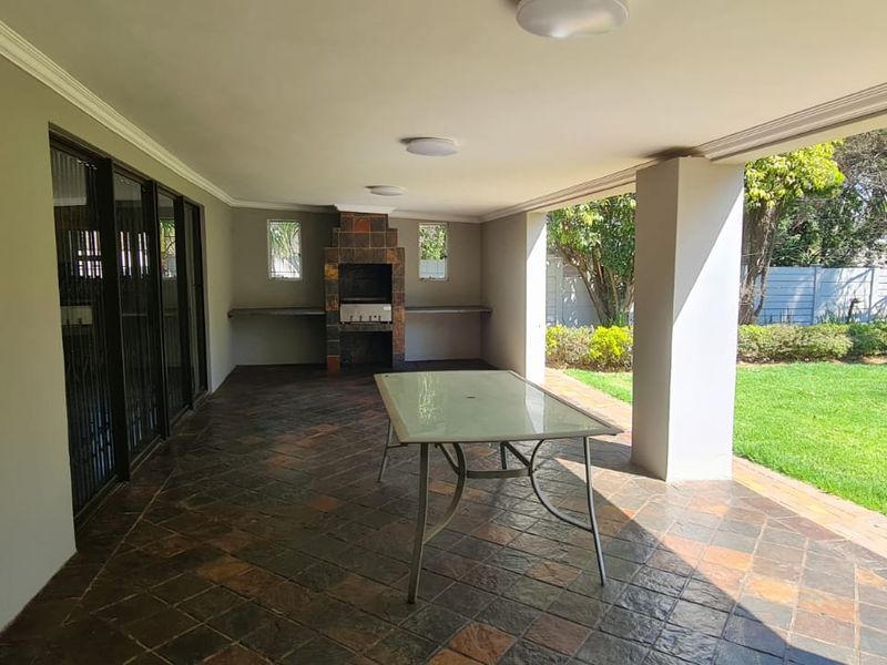 Covered patio area featuring a built-in braai, stone tile flooring, and direct access to the garden, ideal for outdoor entertaining.