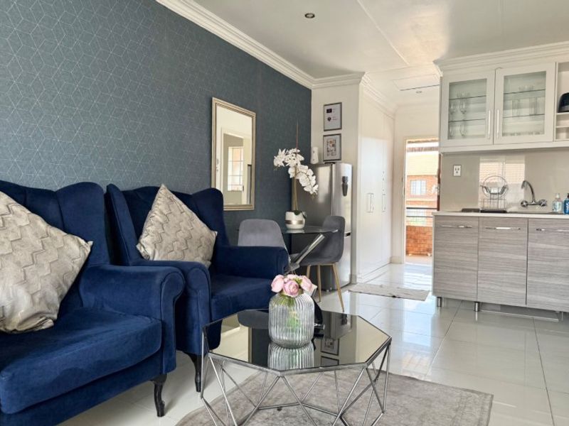 Open-plan living area featuring a modern kitchen with built-in cabinetry, tiled flooring, and recessed lighting, creating a bright and functional space.